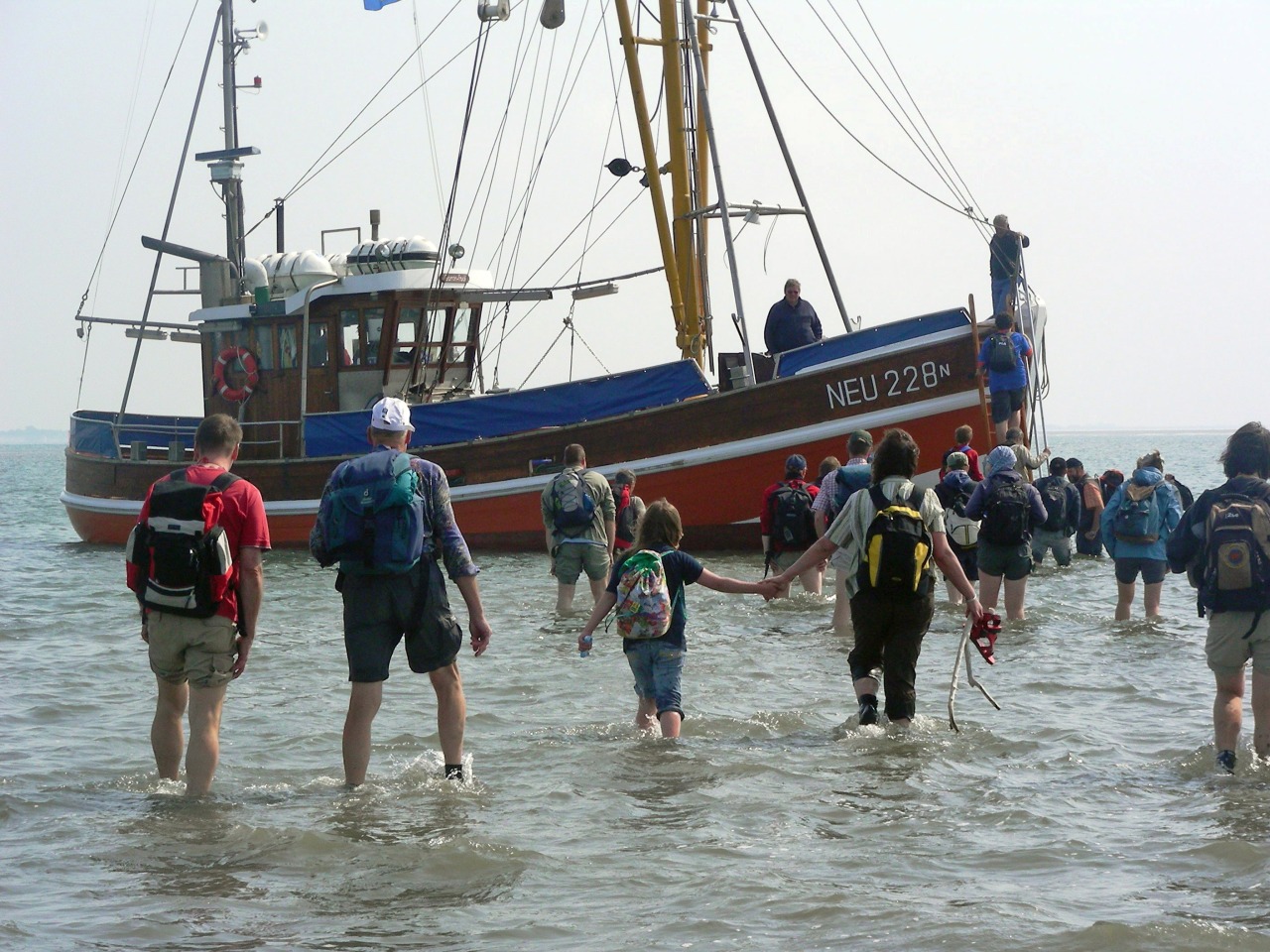 Group of tourists wading through water towards excursion boat. NLPV/ Imke Zwoch.